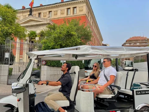 Tuk tuk eléctrico privado pasando frente al Palacio Real de Madrid